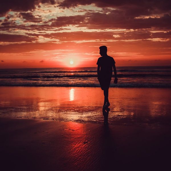 Silhouette of a man in a powerful stance against a vibrant sunrise.